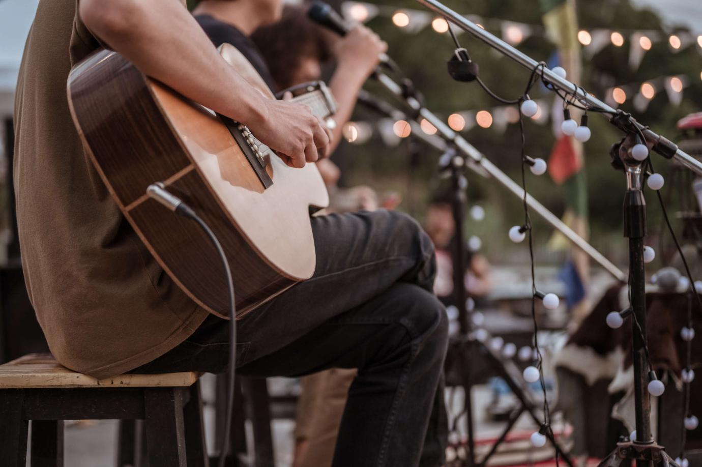 Musician plays guitar at a mini music festival.