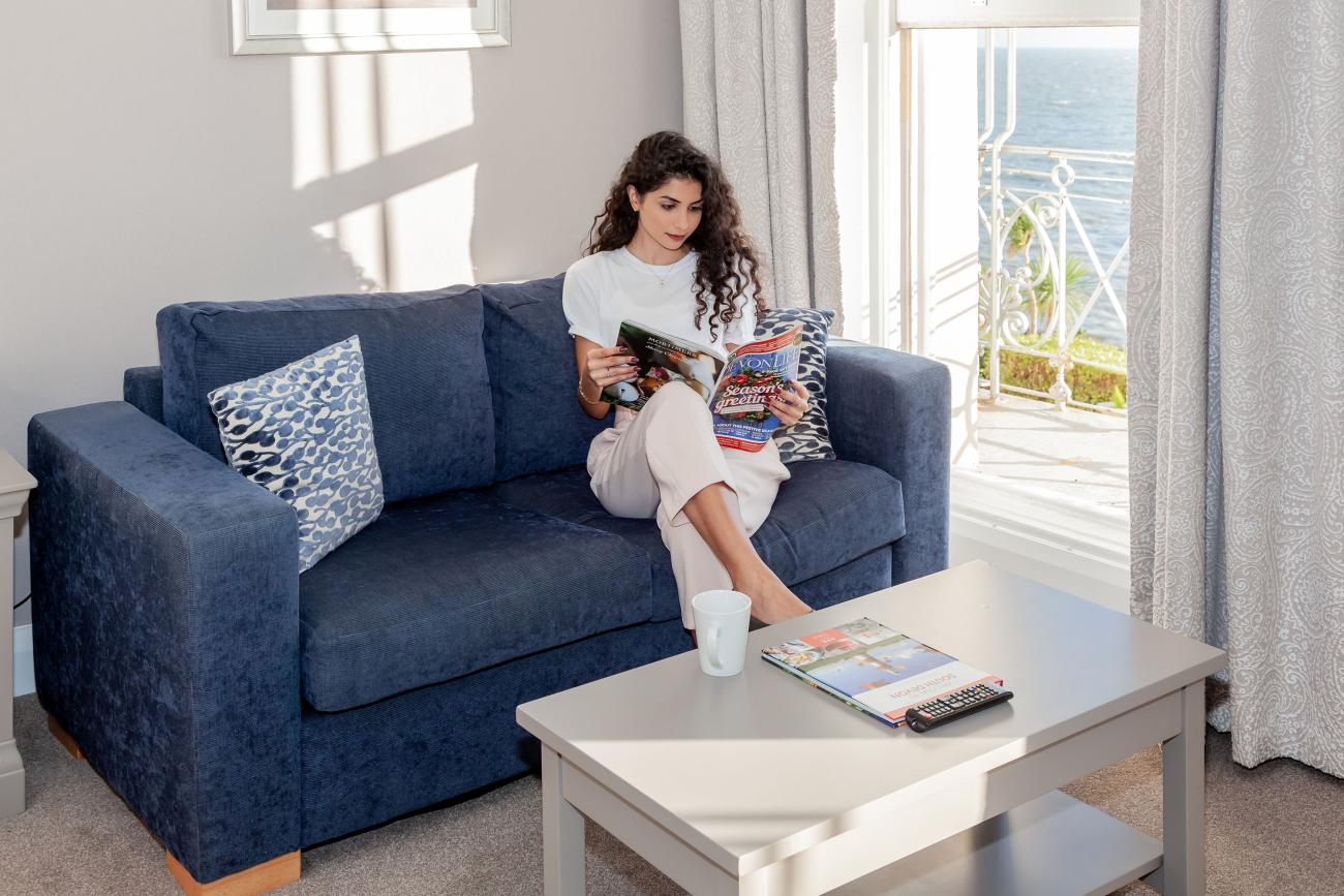 Woman reading a magazine on a sofa in the junior suite at the Osborne Hotel, Torquay