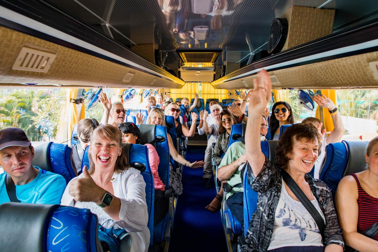 Group of happy people on board a coach in the UK heading to Devon on holiday