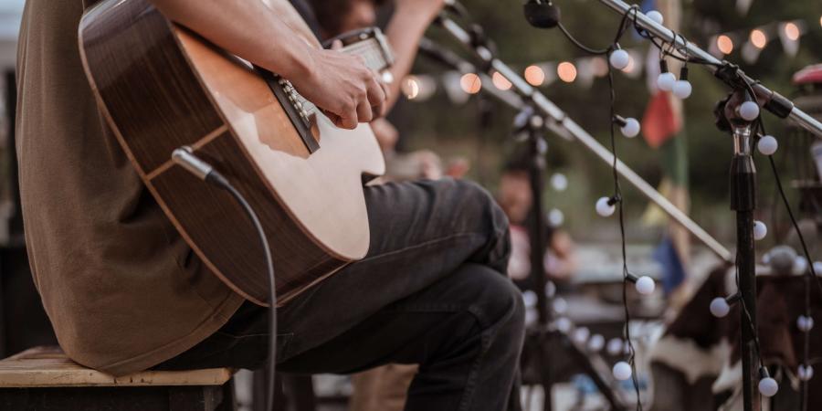 Musician plays guitar at a mini music festival. 